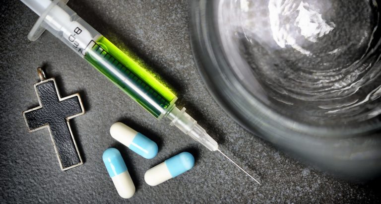 Wasserglas, Kreuz, Tabletten und Spritze, Symbolfoto Sterbehilfe